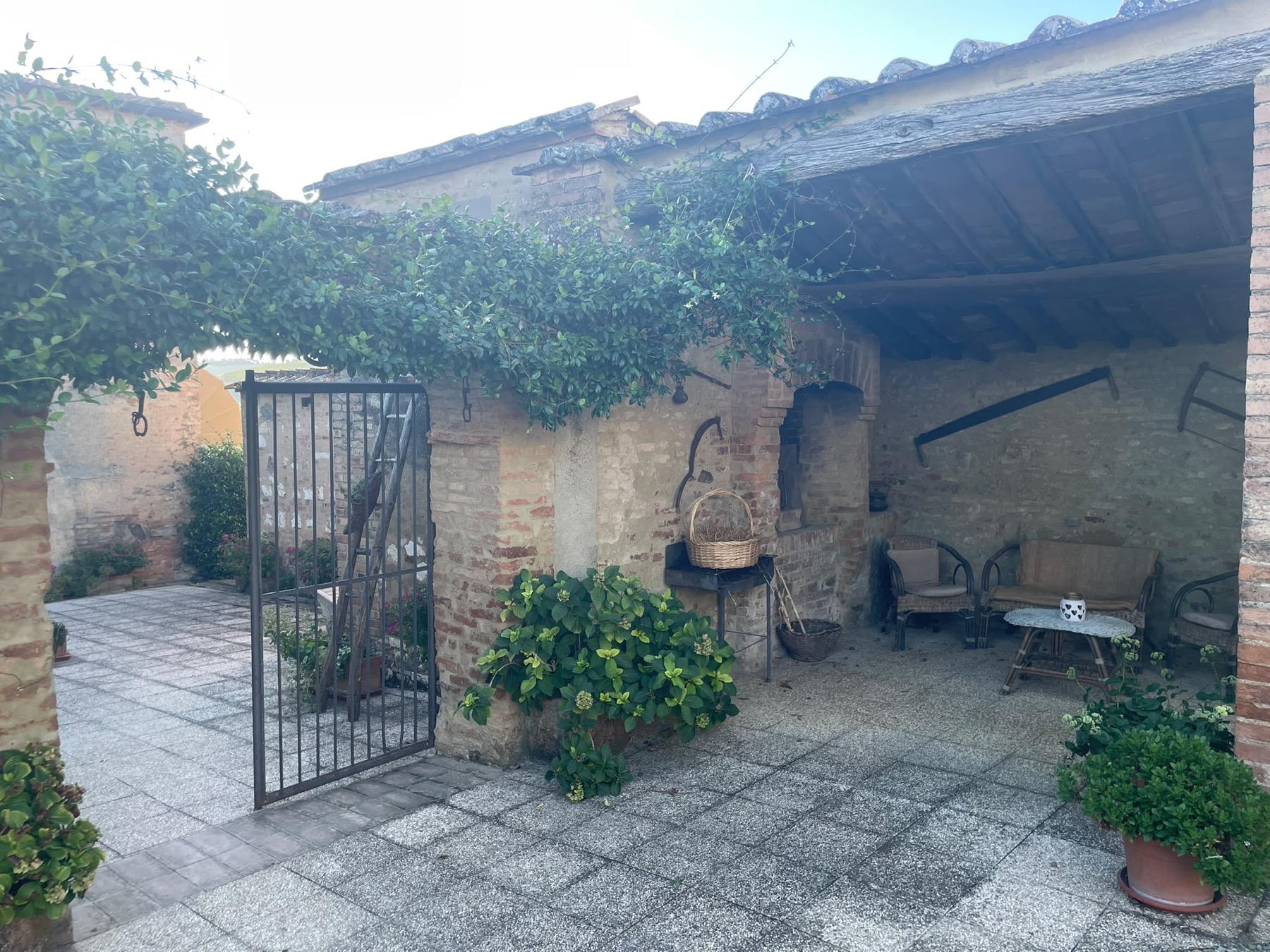 La loggia coperta nel cortile, con le poltrone in vimini e il rampicante in fiore